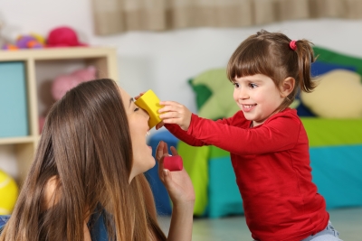 Eine junge Frau und ein Vorschulmädchen spielen und lachen zusammen